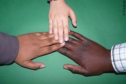 Drei Kinder unterschiedlicher Nationalit&auml;ten legen ihre H&auml;nde freundschaftlich aufeinander