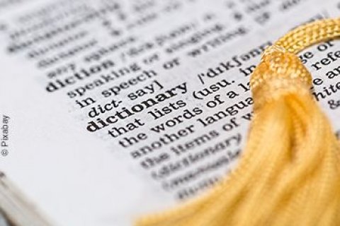 Aufgeschlagener englischer Duden mit einer goldenen Quaste als Lesezeichen.